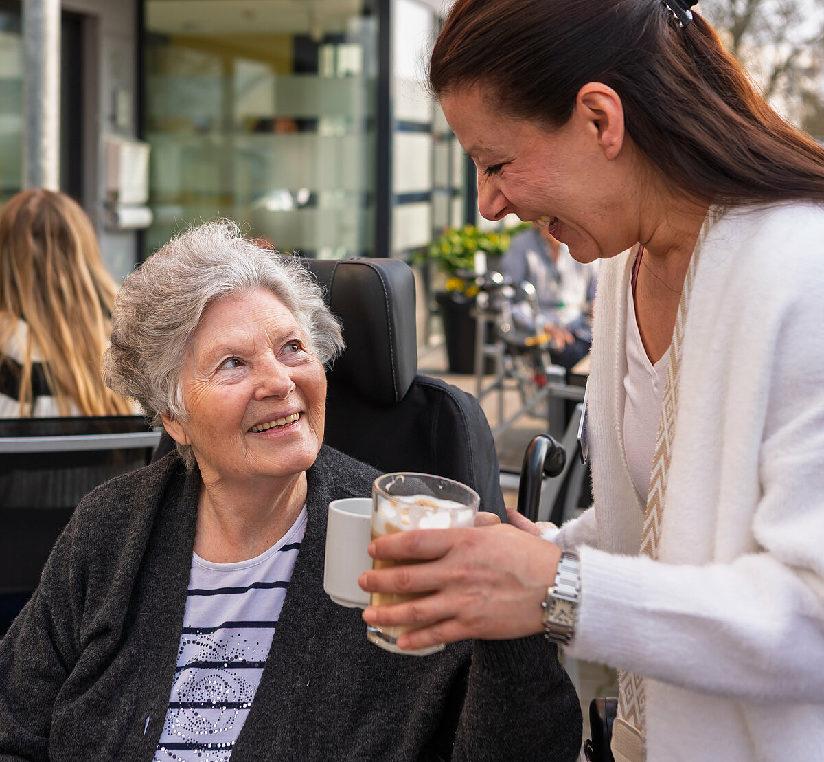 Pflegerin, die einer Seniorin Kaffee bringt