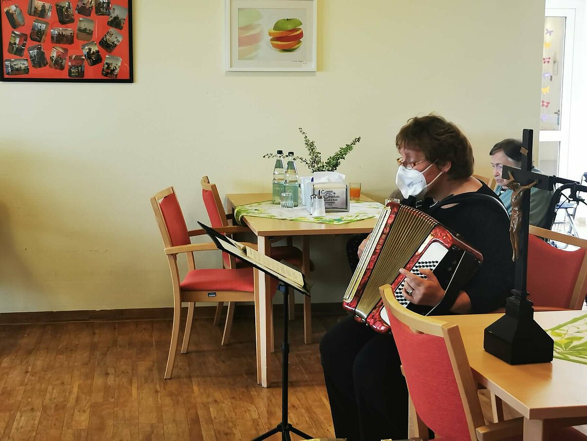 Prädikantin spielt Akkordeon beim Gottesdienst im Seniorenzentrum AGO Rosbach